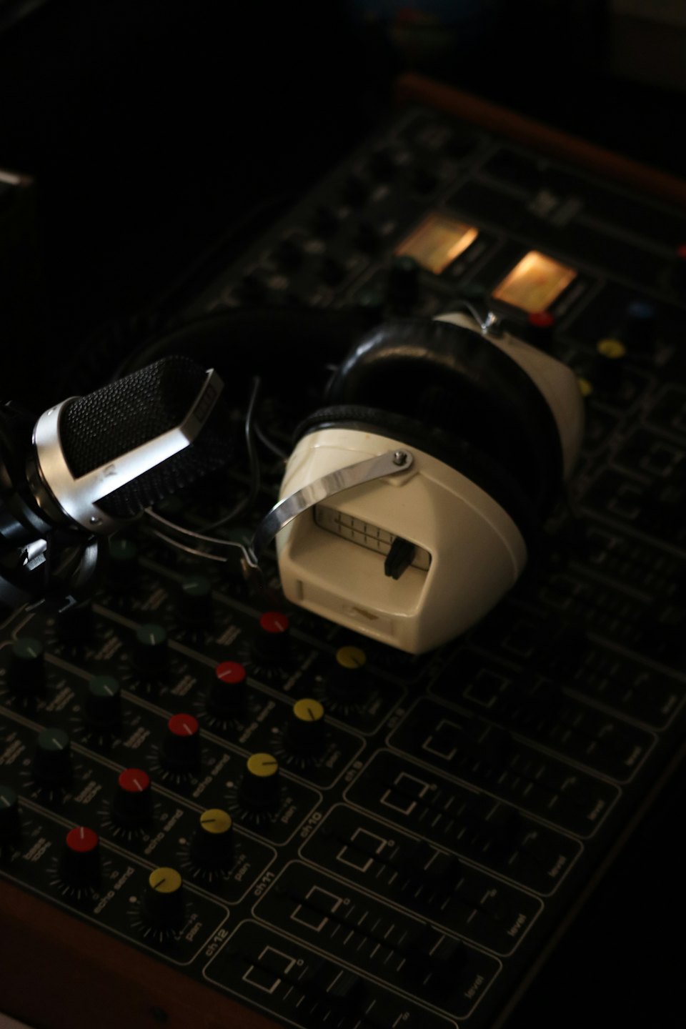 Vintage microphone and headphones on a sound mixing board.